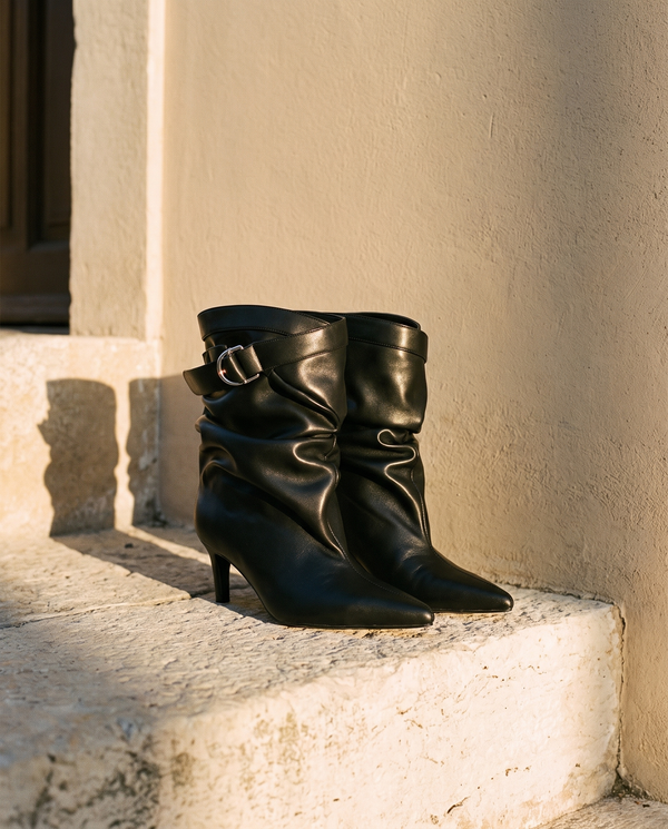 Paire de boots IDA noires posée sur une marche en pierre — A by André