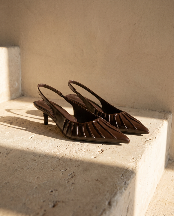 Paire de slingbacks JADE marron posée sur une marche en pierre — A by André