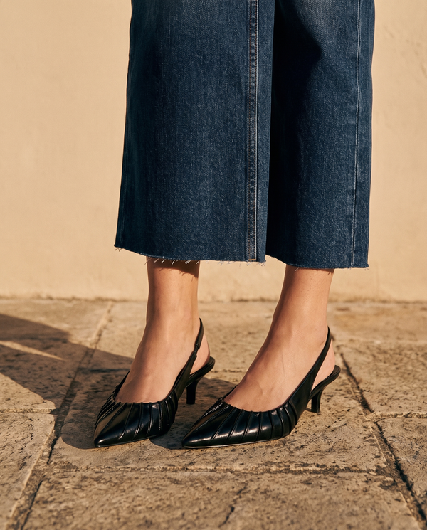 Gros plan sur les chevilles portant les slingbacks JADE noirs — A by André