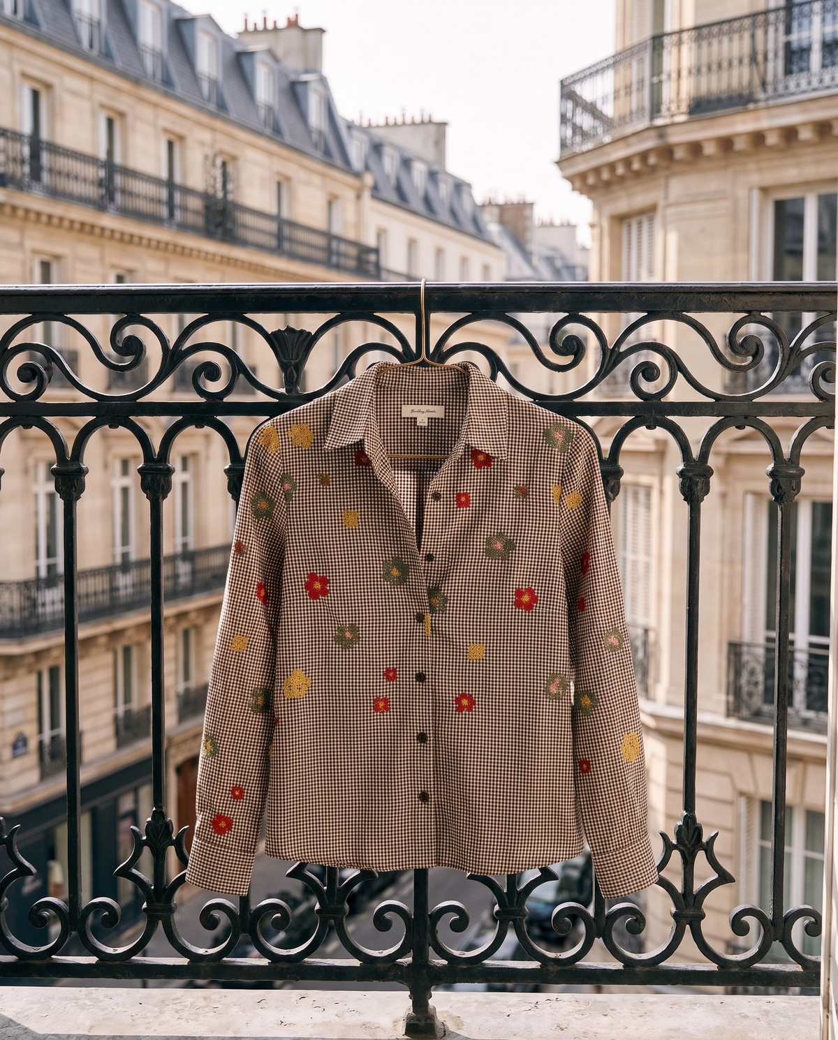 Chemise SIXTINE chocolat suspendue à une grille en fer, rue haussmannienne