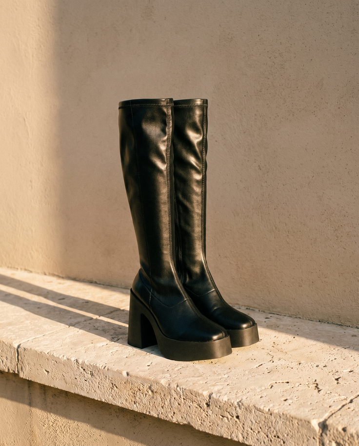 Paire de bottes ADOLINE noires posée sur une marche en pierre — André