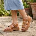 Sandales André Adonis camel à brides réglables, boucles dorées et semelle crantée épaisse pour un look estival.