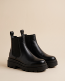 Boots ALCALINA noires debout sur fond beige