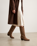 Botte ALESSIA taupe en daim portée, studio mur blanc