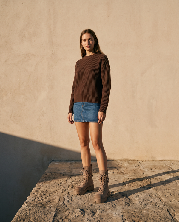 Boots ALMA beige à lacets portées avec une jupe en jean sur une terrasse en pierre — A by André