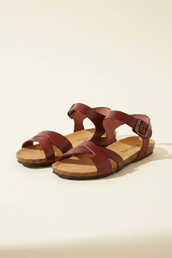 André sandales plates en cuir marron avec brides croisées et boucle à la cheville, semelle ergonomique.