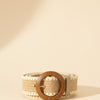 André Oasia taupe woven paper belt with a large wooden circle buckle and decorative stitching.