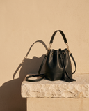 Sac BÉRÉNICE noir Maison André sur une marche en pierre