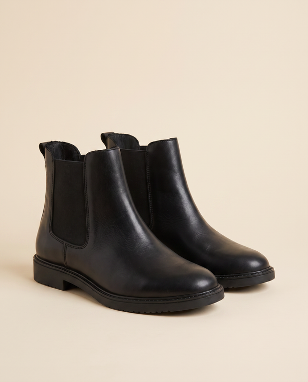 Boots BRUNETTE noires debout sur fond beige