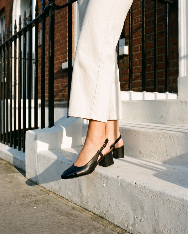 Slingback BRUNIE noire portée, gros plan, un pied posé sur la marche d'une maison londonienne