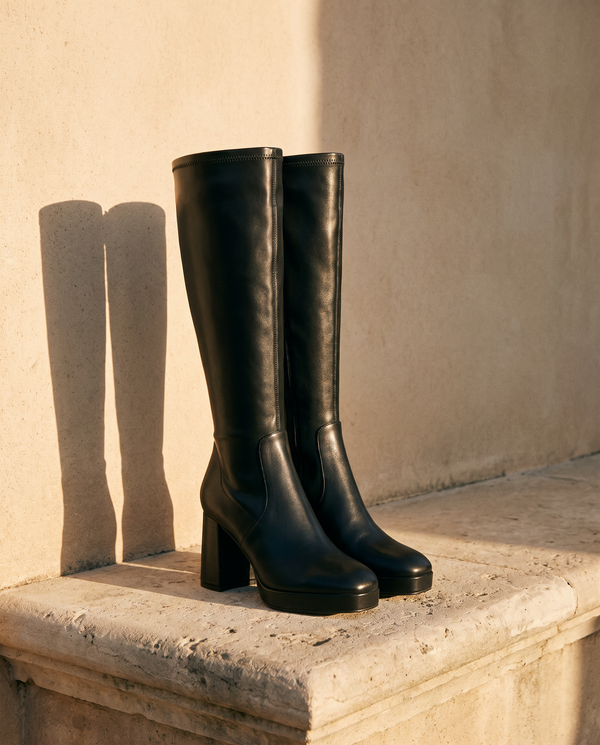 Paire de bottes CALIA noires posée sur une marche en pierre — André