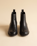 Boots CARAMEL noires debout sur fond beige