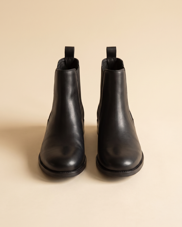Boots CARAMEL noires debout sur fond beige