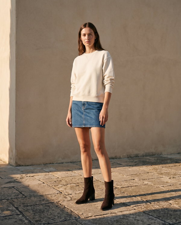 Boots CHARLOTTE marron portées avec une jupe en jean sur une terrasse en pierre — A by André