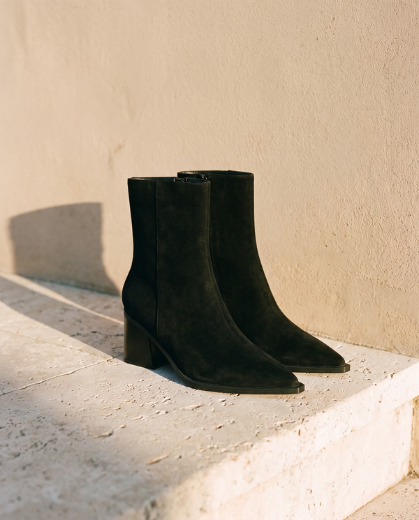 Paire de boots CHARLOTTE noires posée sur une marche en pierre — A by André