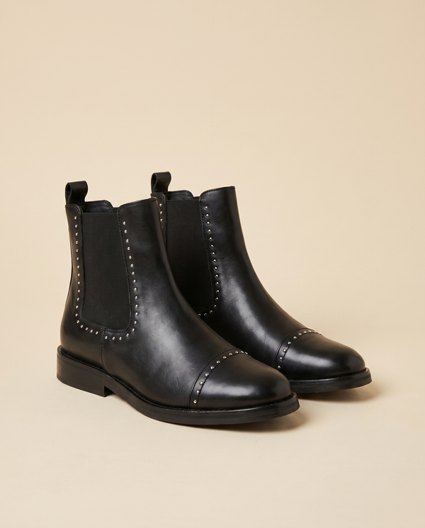 Boots CLOUTEE noir debout sur fond beige