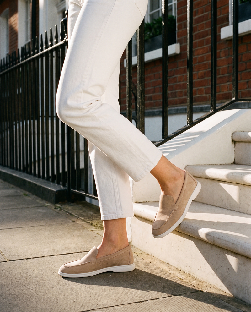 Mocassin CORA beige en daim porté, gros plan, un pied posé sur la marche d'une maison londonienne