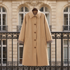 Trench DALILA beige suspendu à une grille en fer, rue haussmannienne
