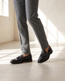 Mocassin EZRA noir porté, pantalon flanelle gris, sol béton clair