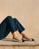 Ballerine GIULIA beige portée, assise sur une marche en pierre