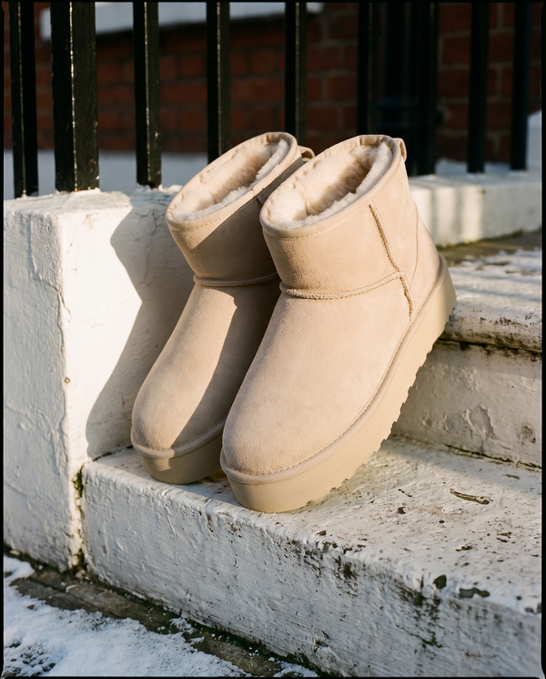 Boots fourrées ICY beige posées sur le perron d'une maison londonienne