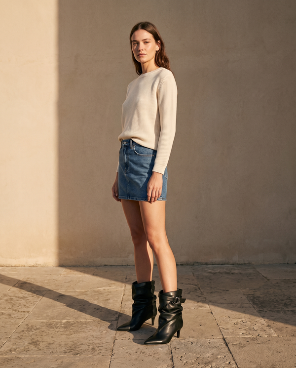 Boots IDA noires portées avec une jupe en jean sur une terrasse en pierre — A by André