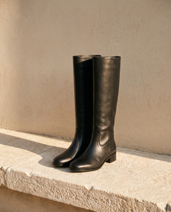 Paire de bottes INGRID noires posée sur une marche en pierre — André