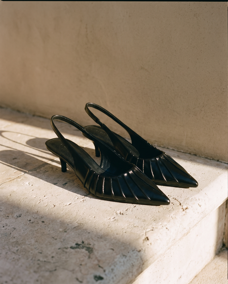 Paire de slingbacks JADE noirs posée sur une marche en pierre — A by André