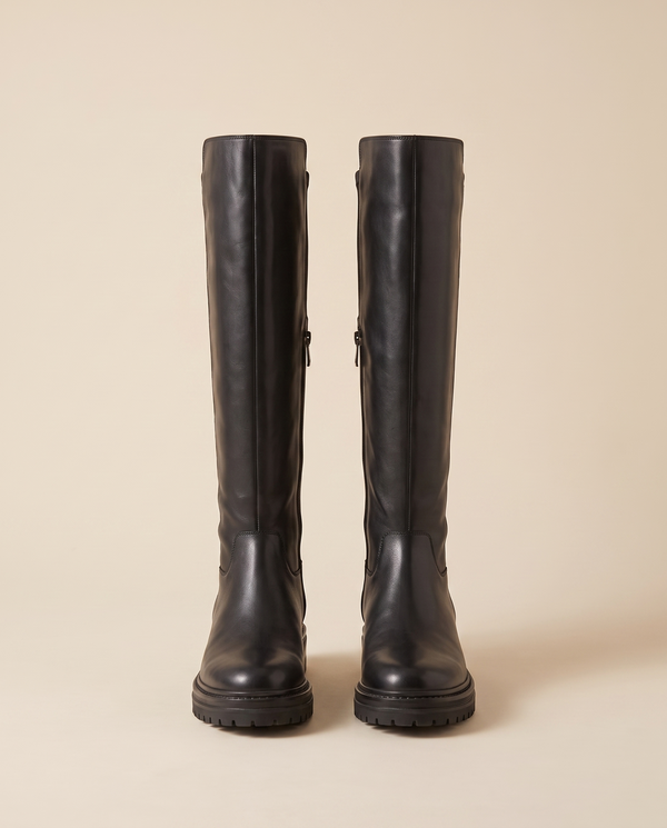Paire de bottes LALIE noires debout sur fond beige