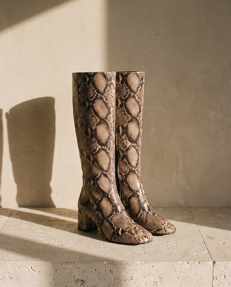 Paire de bottes LEZIA imprimé python posée sur une marche en pierre — André