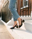 Slingback LUSIA noire portée, gros plan, un pied posé sur la marche d'une maison londonienne