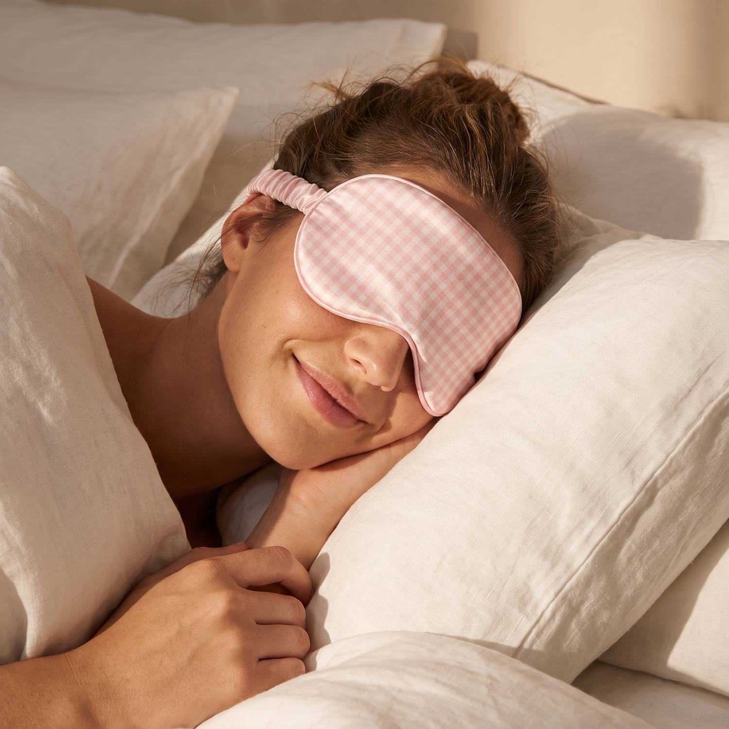 Masque de nuit en soie Ysia rose vichy porté, allongée sur un lit en lin