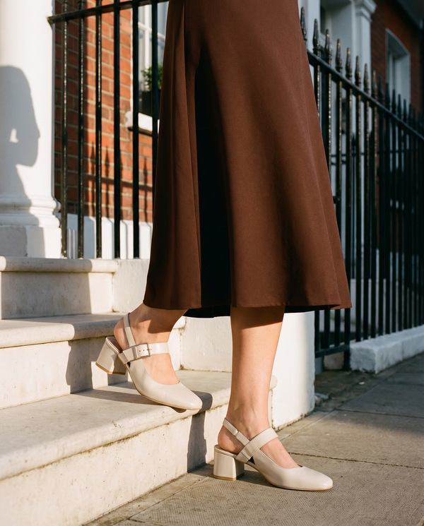 Slingback MONA beige portée, gros plan, un pied posé sur la marche d'une maison londonienne