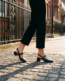 Slingback MONA noire portée, gros plan, sur les pavés d'une rue londonienne