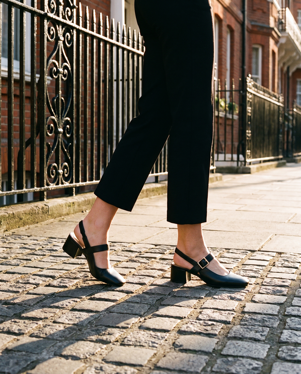 Slingback MONA noire portée, gros plan, sur les pavés d'une rue londonienne