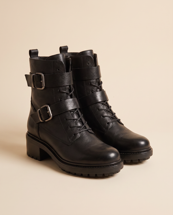 Boots NIMA noires debout sur fond beige