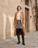 Botte NORAH noire portée avec jupe en tweed, collants opaques et manteau camel