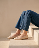 Ballerine POLLY beige portée, assise sur une marche en pierre