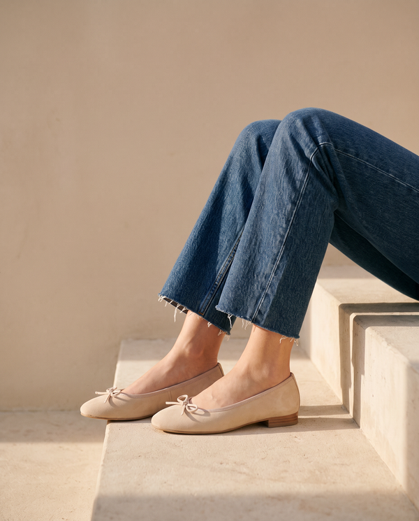 Ballerine POLLY beige portée, assise sur une marche en pierre