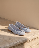 Ballerine POLLY bleu ciel posée sur une marche en pierre, mur enduit beige