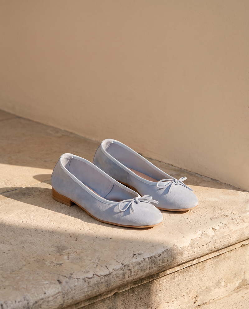 Ballerine POLLY bleu ciel posée sur une marche en pierre, mur enduit beige