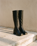 Paire de bottes RATA noires posée sur une marche en pierre — André