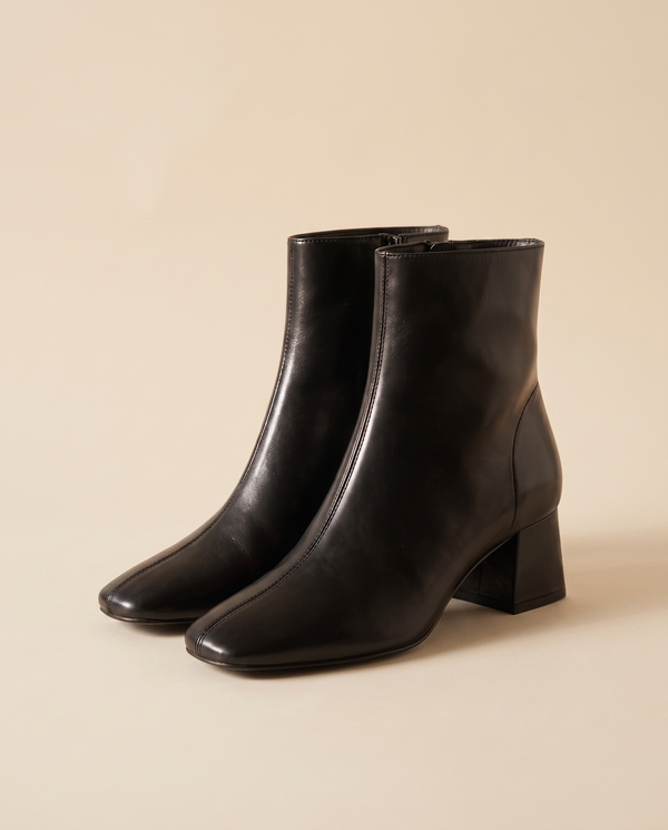 Boots SIMA noires debout sur fond beige