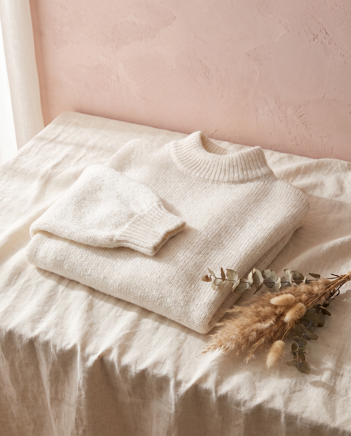 Pull paillettes Solveig écru, posé sur un lin crème, mur rose poudré