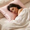 Taie d'oreiller en soie Lunéia rose vichy, femme endormie sur un lit en lin