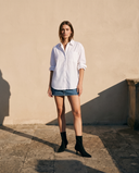 Boots VANINA noires portées avec une jupe en jean sur une terrasse en pierre — A by André